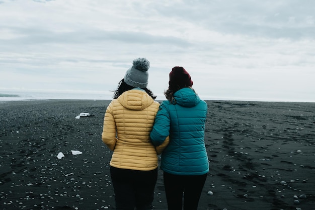 새로운 땅 여행을 탐험하는 아이슬란드에서 검은 모래의 무한한 길을 걷는 여성 커플