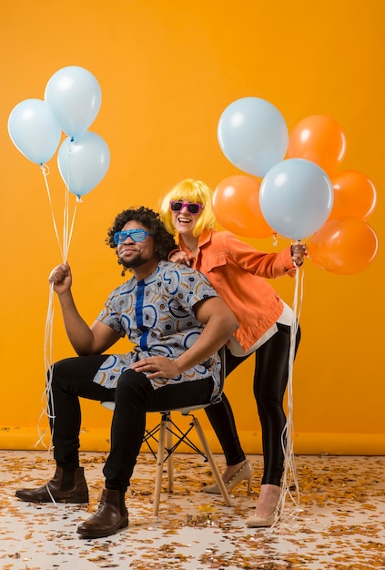 Foto coppia alla festa divertendosi e tenendo palloncini