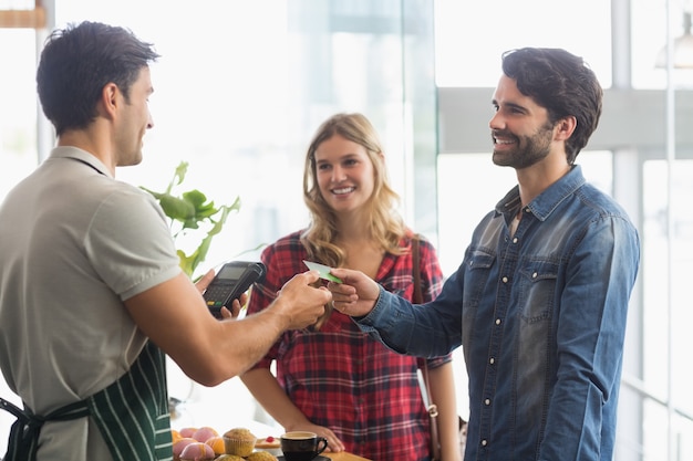 Photo couple paying bill at coffee shop using card bill