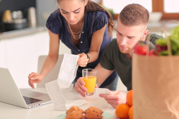 Couple paying their bills with laptop in kitchen at home