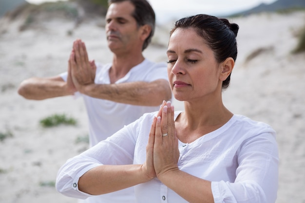 Couple performing yoga on beach