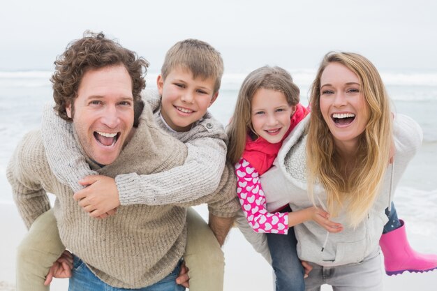 Couple piggybacking kids at the beach