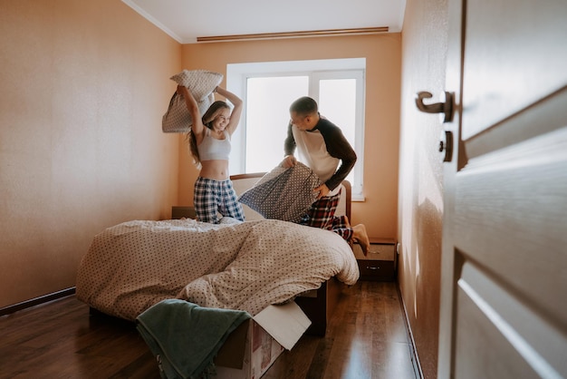 Photo couple playing pillow fight on bed at home