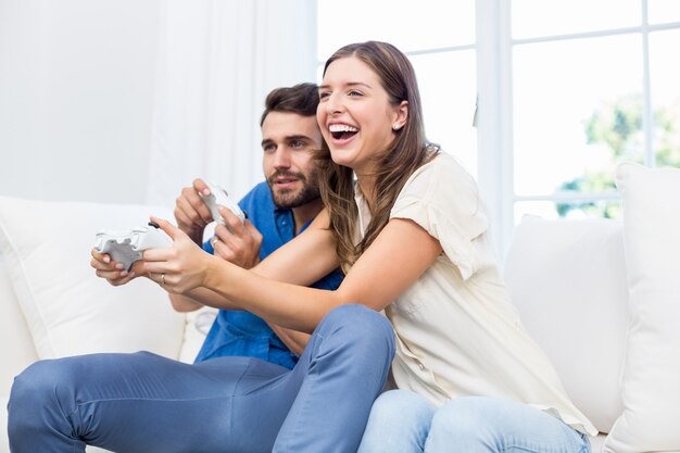 Couple playing video game while sitting on sofa 