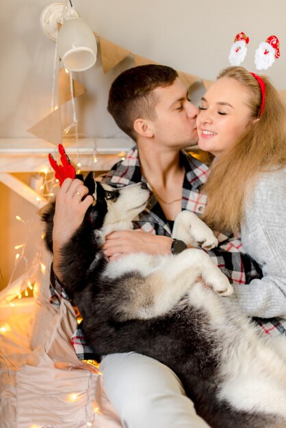 Couple playing with dog in bedroom