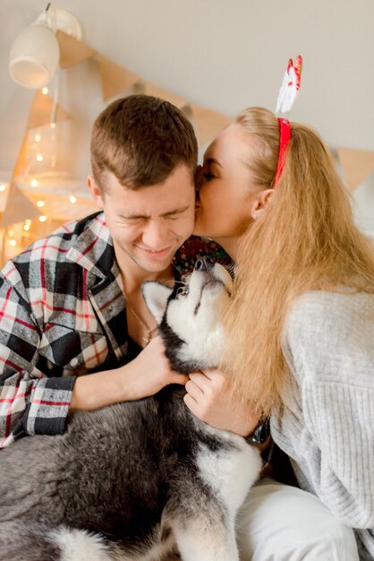 Couple playing with dog in bedroom