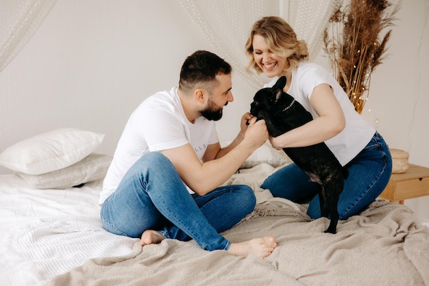 Couple playing with French Bulldog in bed