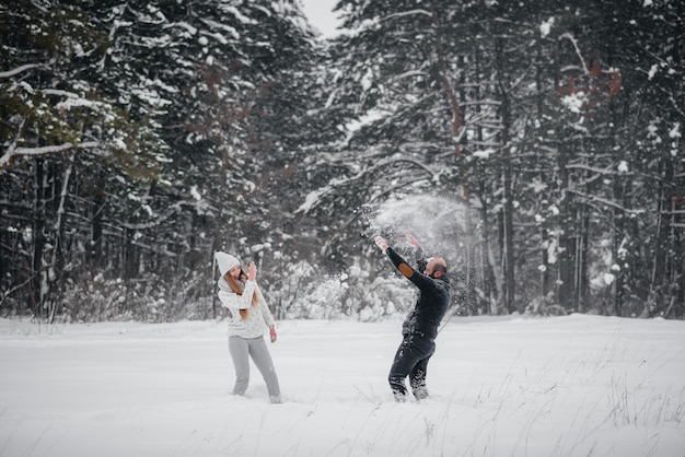 Coppia che gioca con la neve nella foresta.