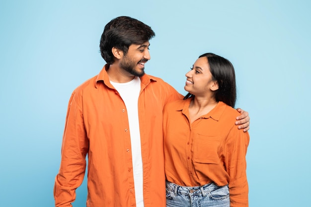 Couple posing in orange shirts on blue background