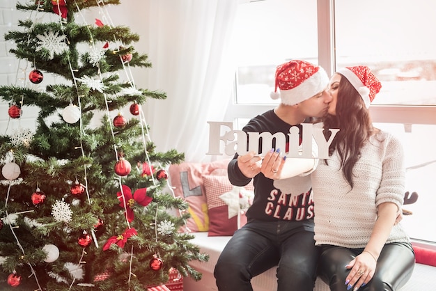 Couple posing with word 'family' in christmas studio