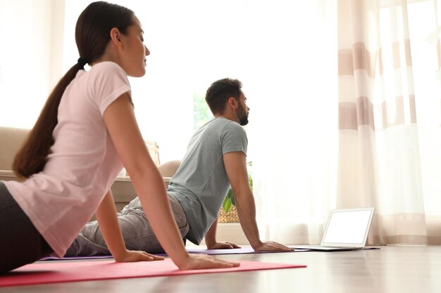 Couple practicing yoga while watching online class at home during coronavirus pandemic Social distancing