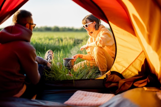 Couple prepare food while traveling with tent on nature