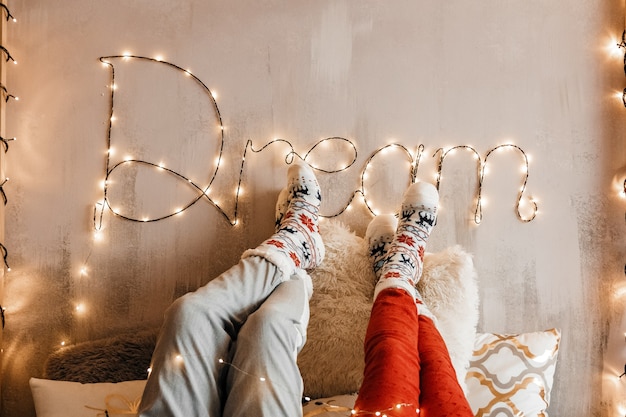 Couple put their legs upon a decorated wall with garlands. Dream.