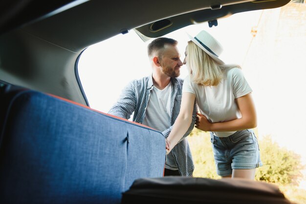 Coppia che mette le valigie nel bagagliaio dell'auto per un viaggio