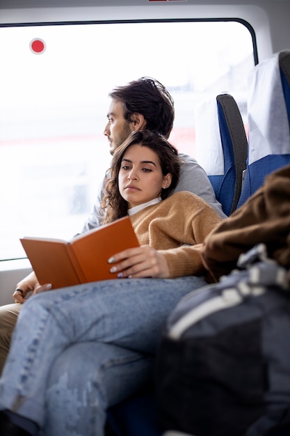 Foto coppia che legge un libro mentre si viaggia in treno