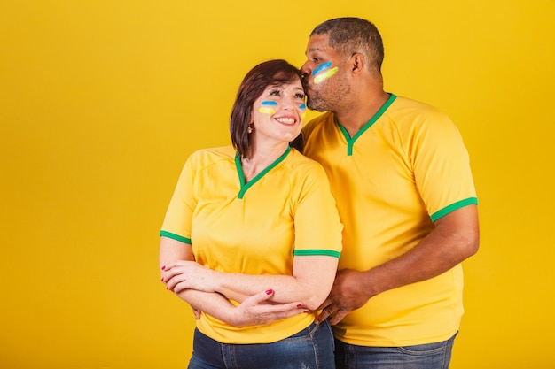 Foto coppia donna dai capelli rossi e uomo nero tifosi brasiliani di calcio braccia incrociate sorridendo alla telecamera