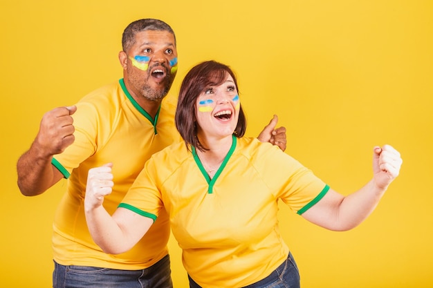 Couple redhaired woman and black man Brazilian soccer fans celebrating