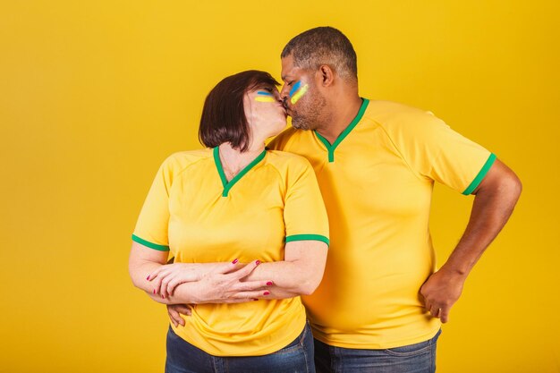 Couple redhaired woman and black man brazilian soccer fans giving kiss