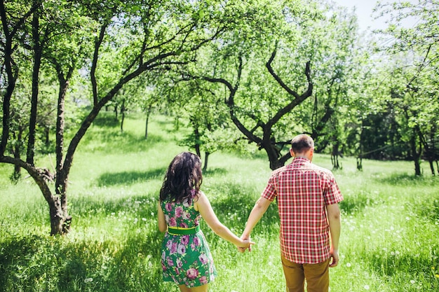 Couple relax in green garden. Lovely couple walk in green meadow.