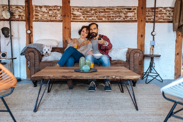 Couple relaxed at home in the couch watching tv and eating popcorn