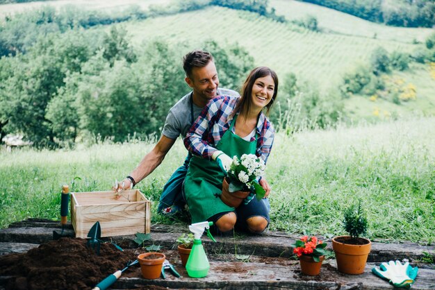 Coppia il rilassamento e la piantatura dei fiori nel loro cortile della casa della campagna