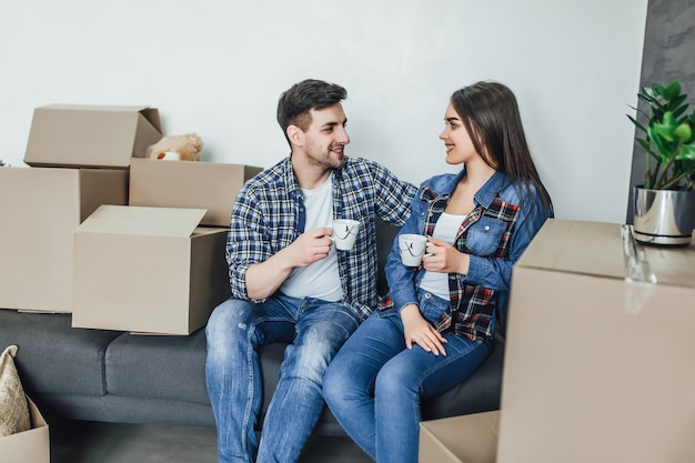 Couple relaxing on sofa with hot drink In new home