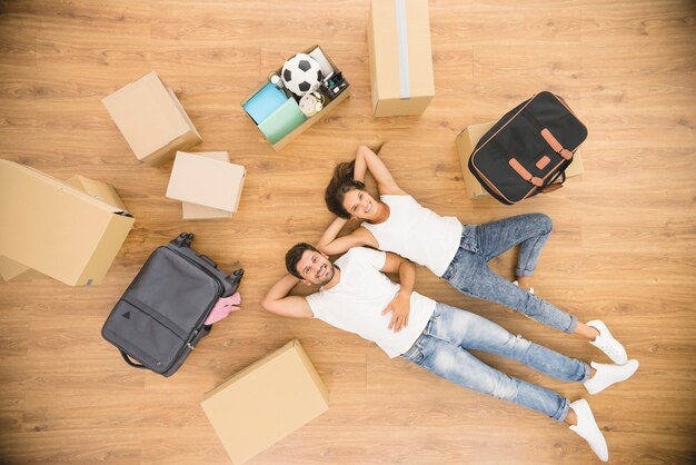 The couple rest on the floor near carton boxes. view from above