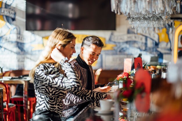 Couple in restaurant having breakfast using mobile phone.