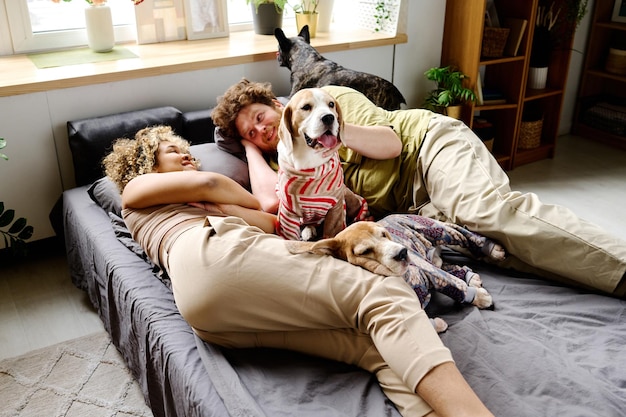 Photo couple resting in bed with dogs