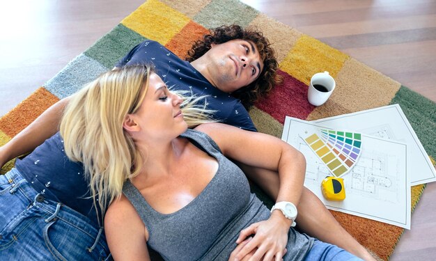 Couple resting lying on the carpet of their new house