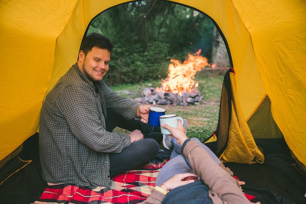 Couple resting in tent with view on fire