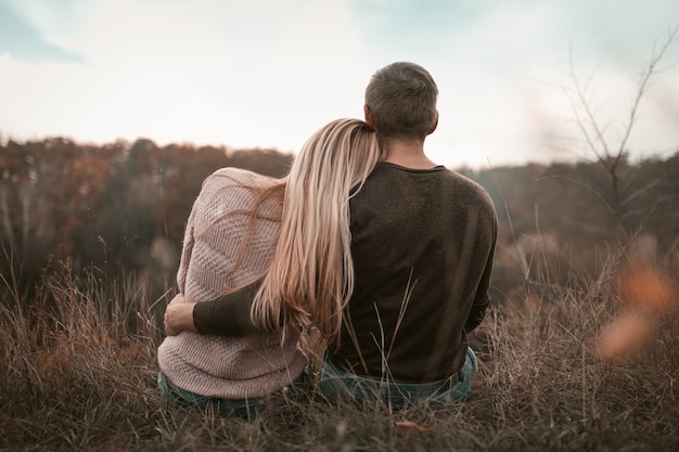 Couple Rests Sitting On Rock In Nature Outdoors