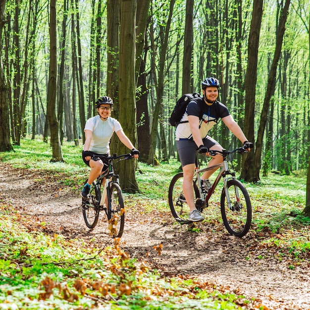 Couple riding bicycle in forest in warm day