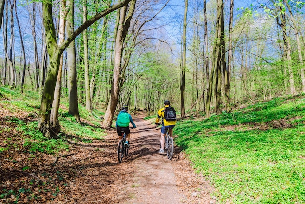 Couple riding bicycle in forest in warm day