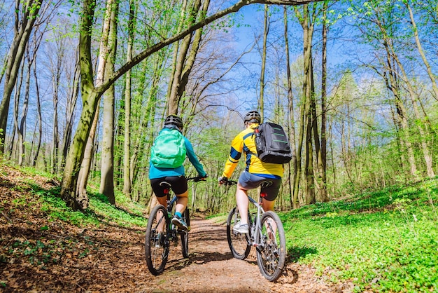 Couple riding bicycle in forest in warm day