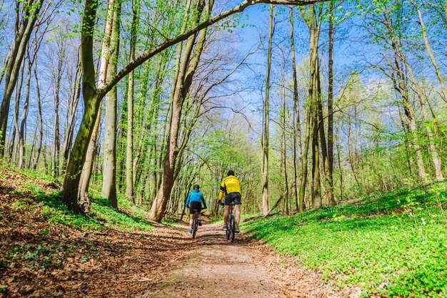 Couple riding bicycle in forest in warm day