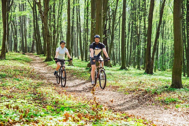 Couple riding bicycle in forest in warm day