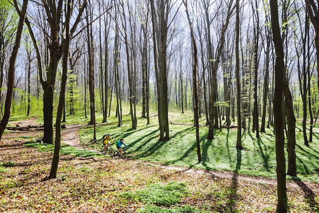 Couple riding bicycle in forest in warm day