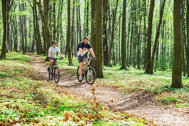 Couple riding bicycle in forest in warm day