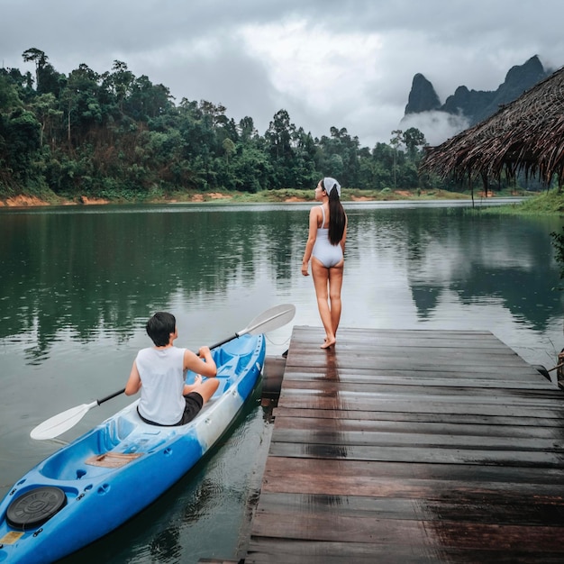 태국 Khao Sok Cheow Lan Dam Ratchaprapha Dam에서 편안한 휴가나 휴가를 보내기 위해 떠다니는 뗏목에서 보트를 타는 커플