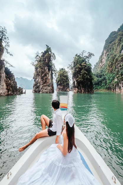 Photo couple riding a long tail boat to khao sok national park phang nga province khao sok national park with a long tail boat for tourists cheow lan lake ratchaprapha dam on holiday