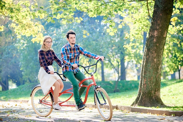 couple riding tandem bicycle at city street