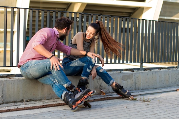 Couple on rollerblades is sitting.