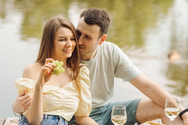 Couple on romantic picnic on summer day with champagne and grapes. Sweet life. Happiness and serenity. Wonderful moments of life. Super day. Romantic relationships. Tenderness and care.