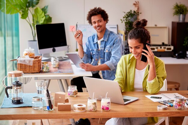 Photo couple running online business making boutique candles at home using computer tech and mobile phone