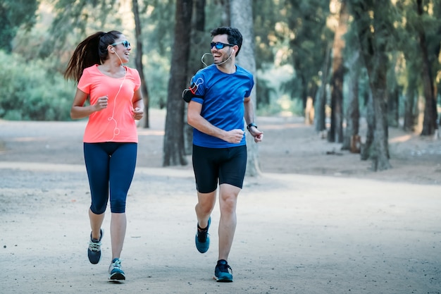 Couple running in a park smiling and listening to music