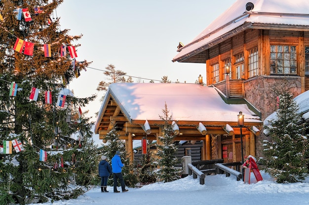 Couple at Santa Claus Office in Santa Village with Christmas trees, Lapland, Finland, on Arctic Circle in winter.