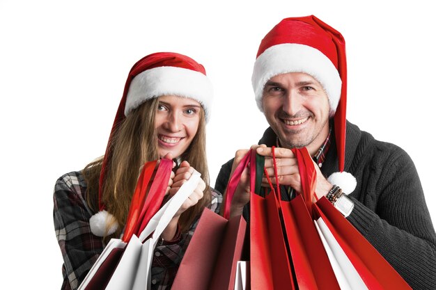 Couple in Santa hats with christmas shopping bags isolated on white background