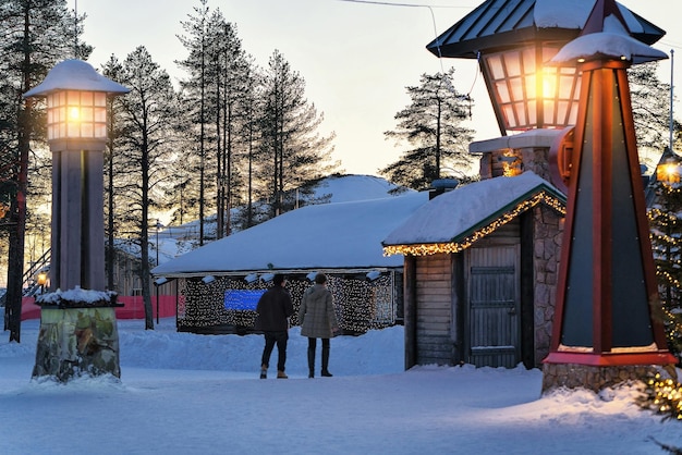 冬の北極圏のラップランド、フィンランド、スカンジナビアのクリスマスツリーとサンタ村のカップル。