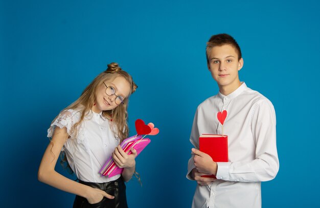 A couple of schoolchildren are teenagers on Valentine's Day on a blue background